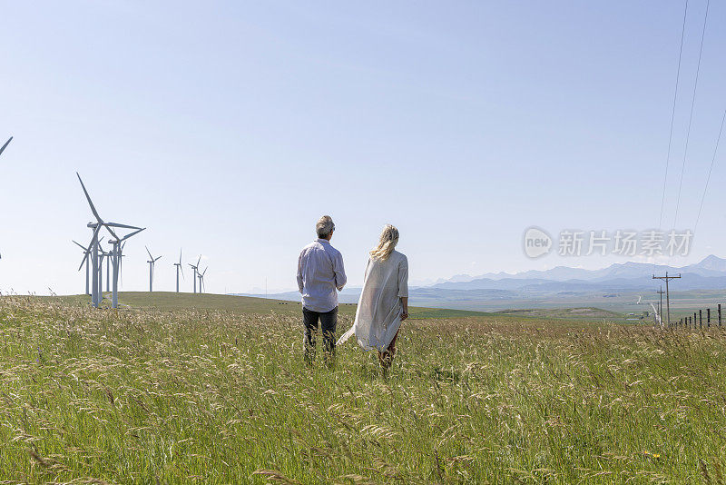 一对夫妇在风力涡轮机下的草地上放松
