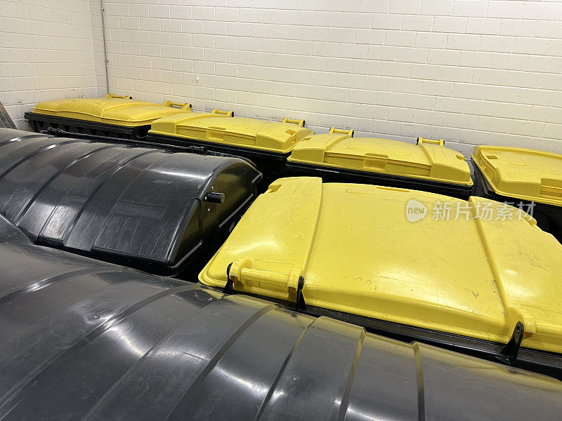 黄色和黑色的回收箱，用于德国公寓垃圾室的塑料和残余废物
