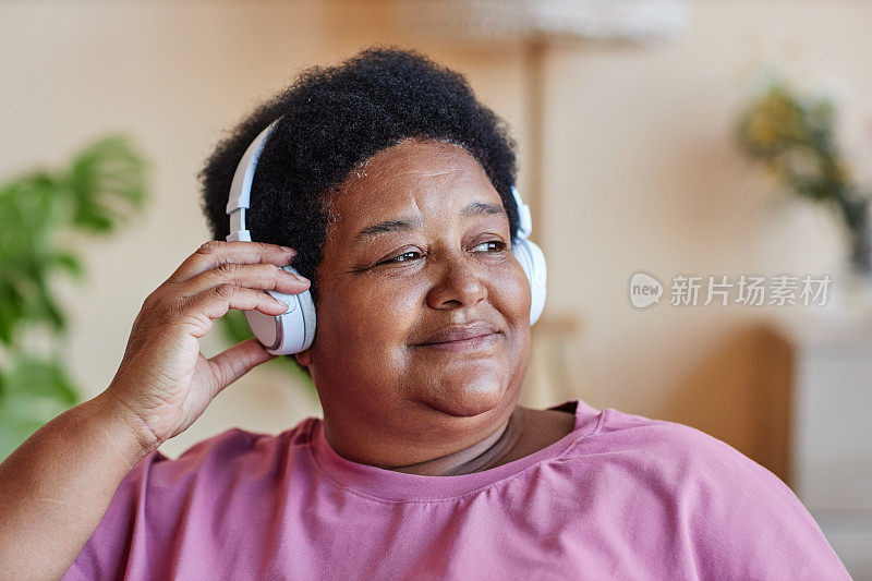安详的非裔美国老妇人戴着耳机听音乐