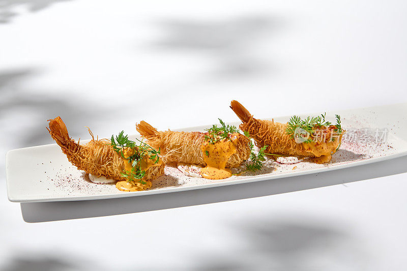 传统的希腊开胃菜——用白色盘子包裹的虾。夏日的脆皮虾。虾开胃菜炸在kataifi面团。现代风格的脆皮对虾。
