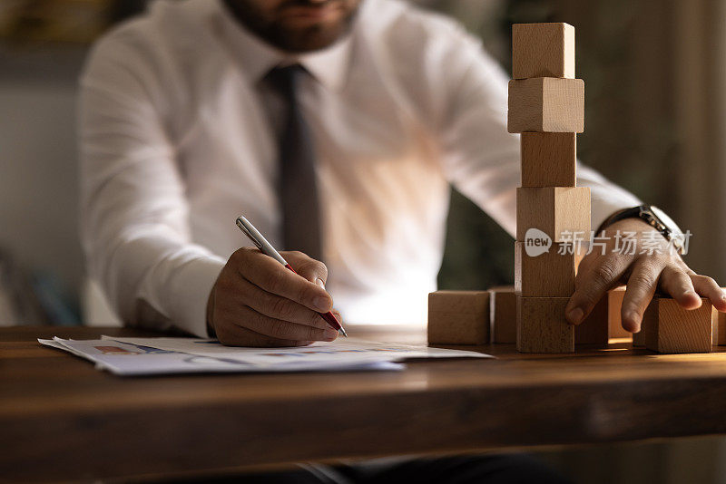 商人手拉或放置木块在塔和半金字塔在现代办公室。商业计划和战略。
