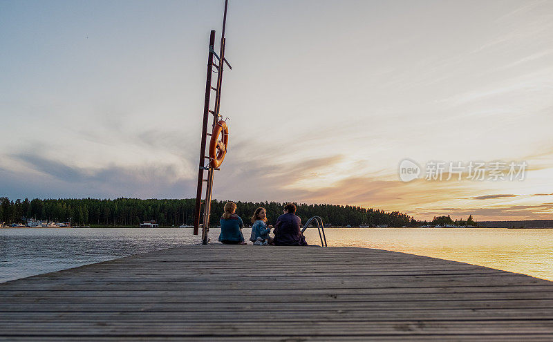 一家人，白人妇女和一个孩子，一个8岁的女孩，看着湖上的日落。