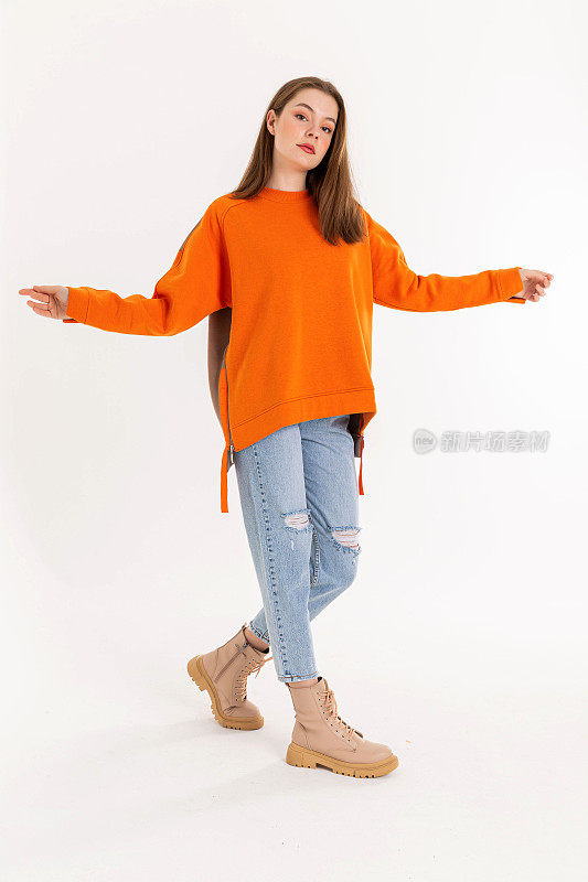 身穿橙色毛衣和蓝色牛仔裤的黑发年轻女子。
