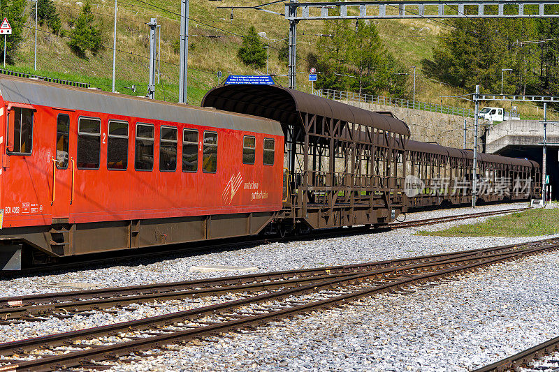 汽车穿梭列车停在火车站在瑞士阿尔卑斯山的村庄的缩小视角。