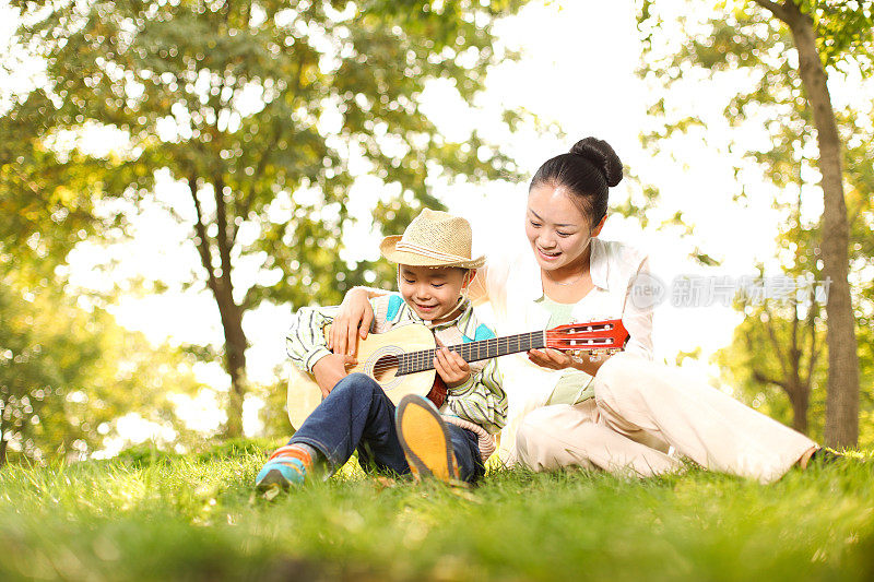 妈妈和儿子在公园里弹吉他