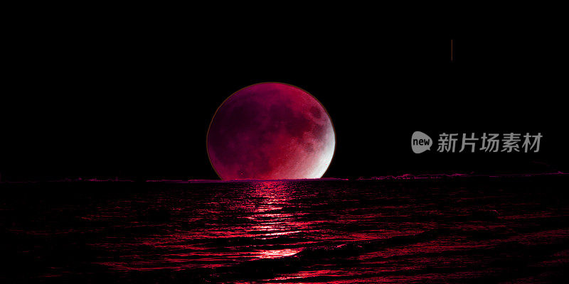 血红色的月亮在海洋的地平线上