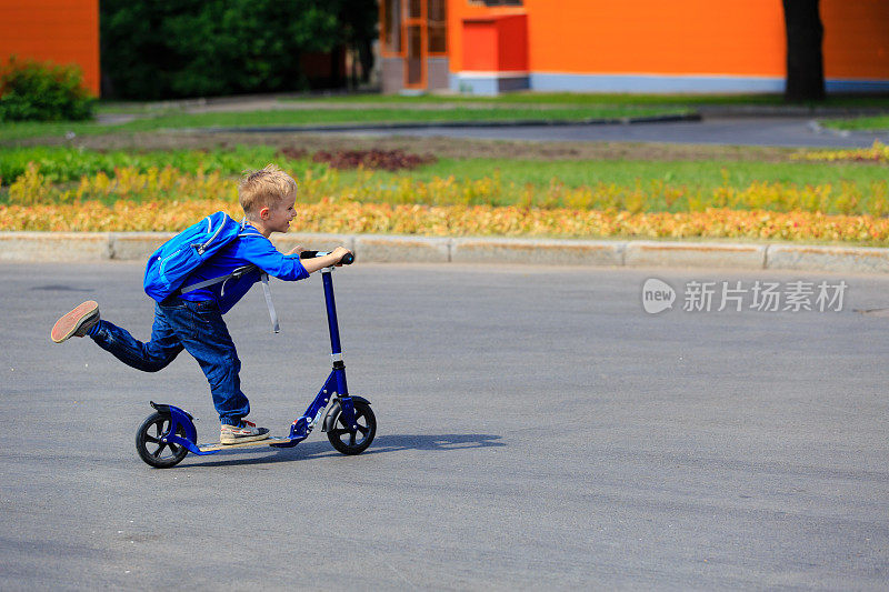 小男孩骑着滑板车在城市里