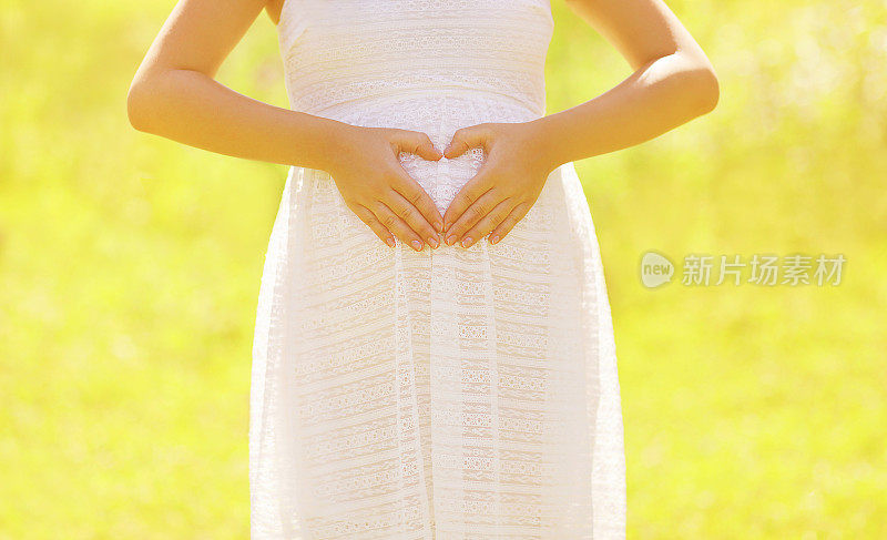 阳光概念孕妇显示手在形状的心脏