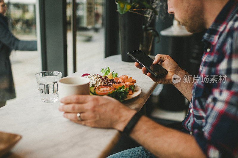 一名男子在咖啡馆餐厅玩他的智能手机