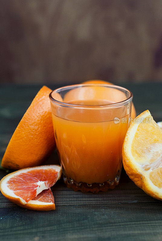 玻璃橙汁和一组橘子在深色的板上