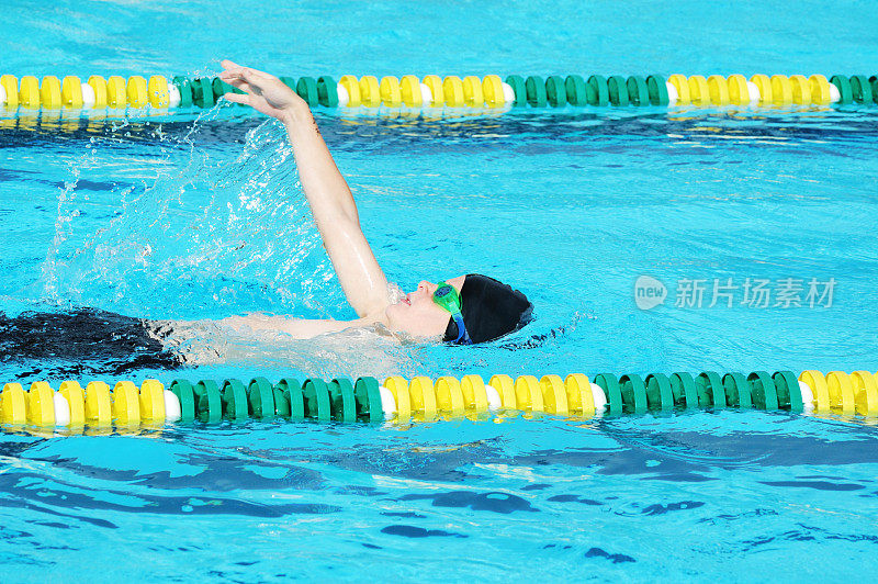 年轻男子运动员在比赛中游泳仰泳