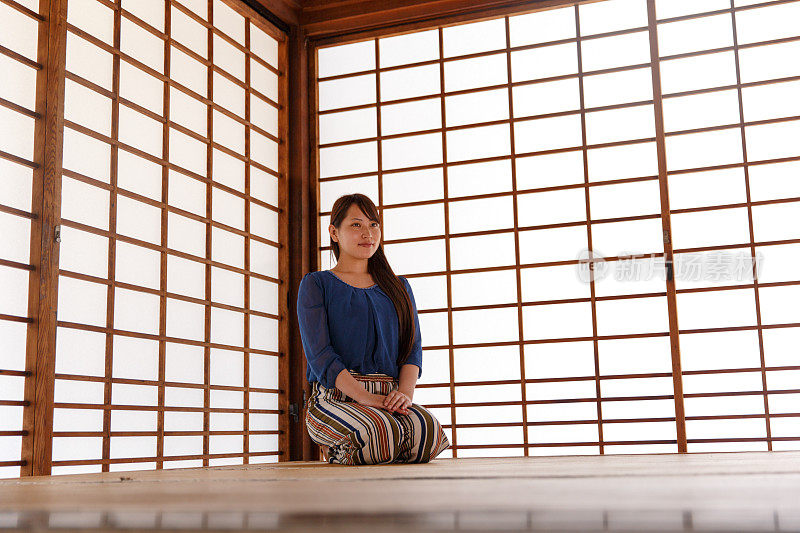 年轻女子坐在日式榻榻米房间里