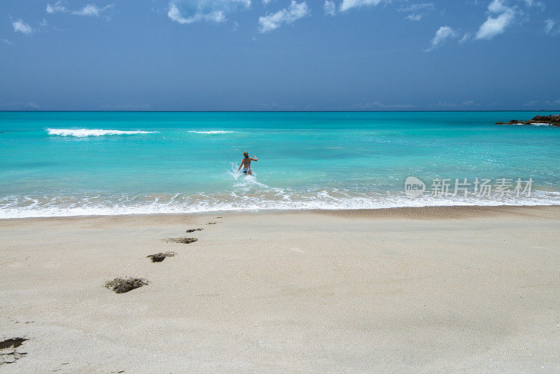 女人跑进温和的海浪，海滩