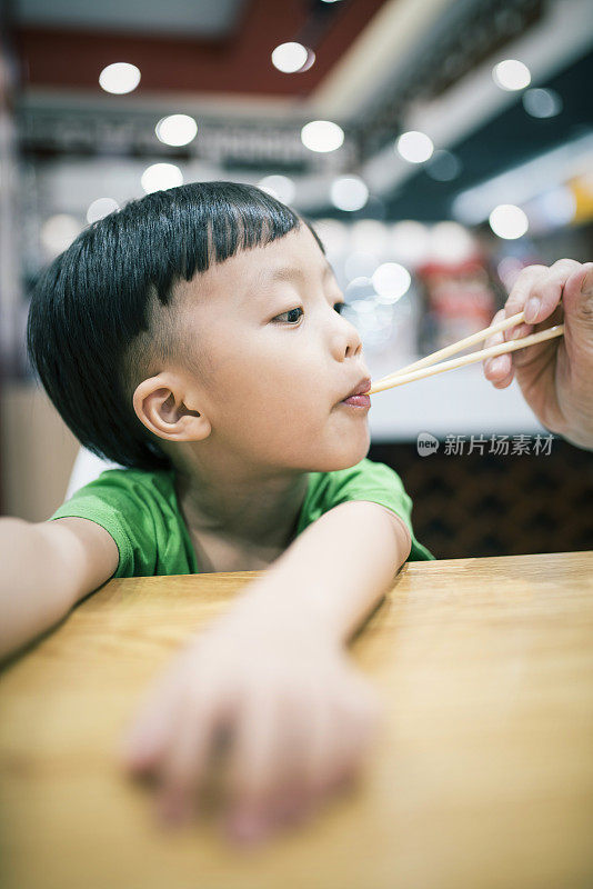 快乐的亚洲孩子用筷子吃美味的面条