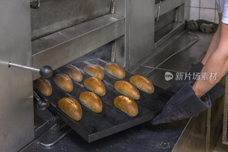 这是面包师从烤箱里拿出面包的特写