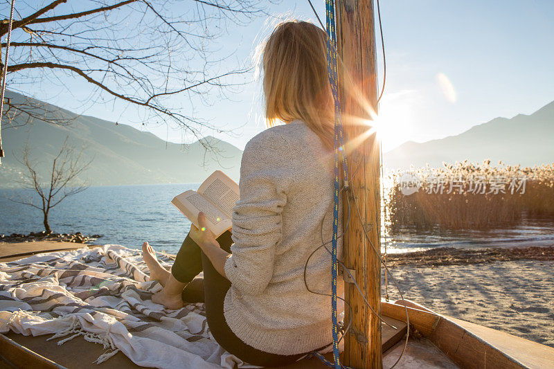 年轻女子在湖边放松看书