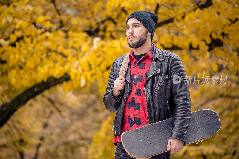 年轻的滑板者在秋天的公园