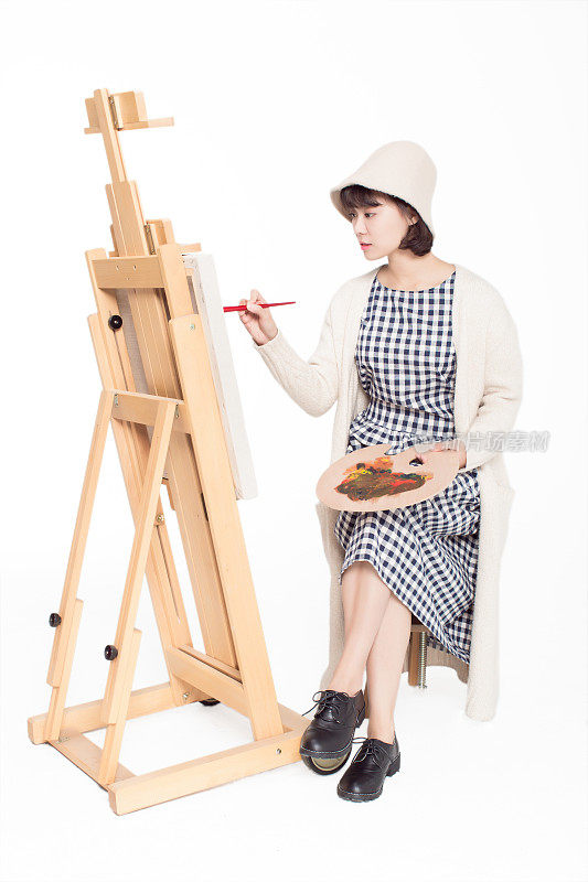 中国画家美丽的女孩，坐在写生板前，拿着调色板
