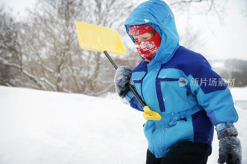 孩子在缤纷的冬天穿铲雪