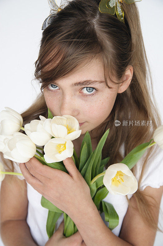 一个蓝眼睛的女孩捧着一朵白色的郁金香，闻着花香