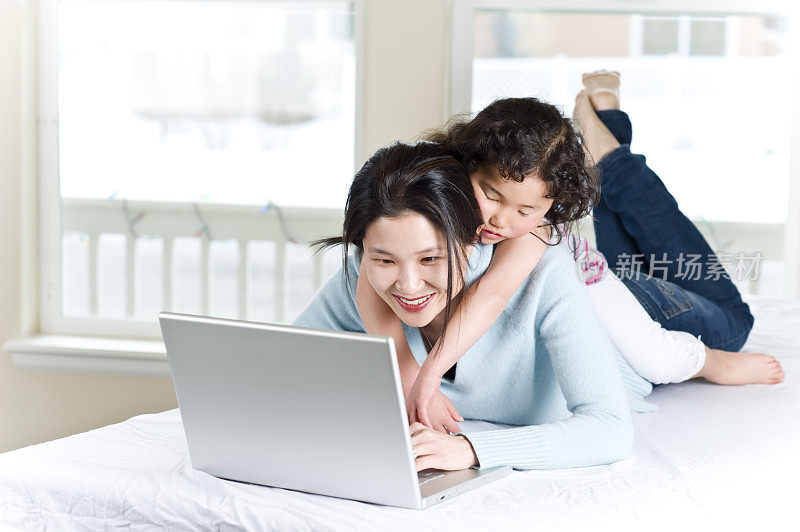 亚裔美国妈妈和女儿使用笔记本电脑