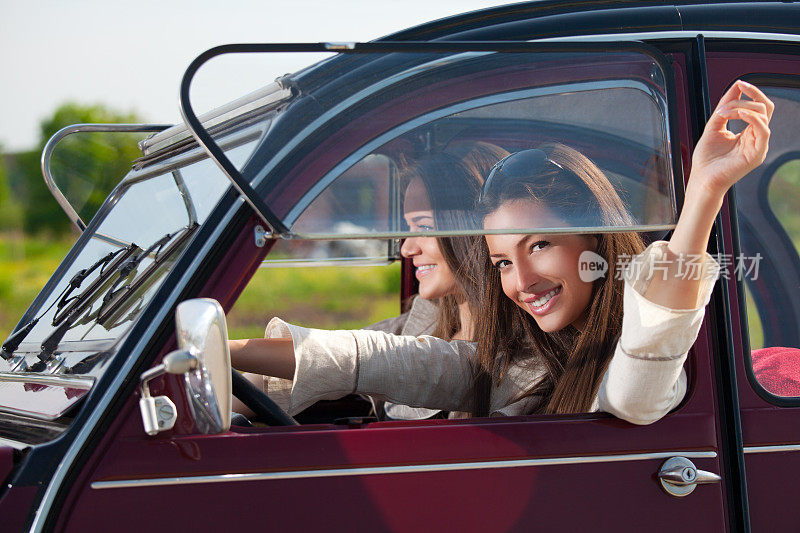 两个快乐的女人坐在老爷车里