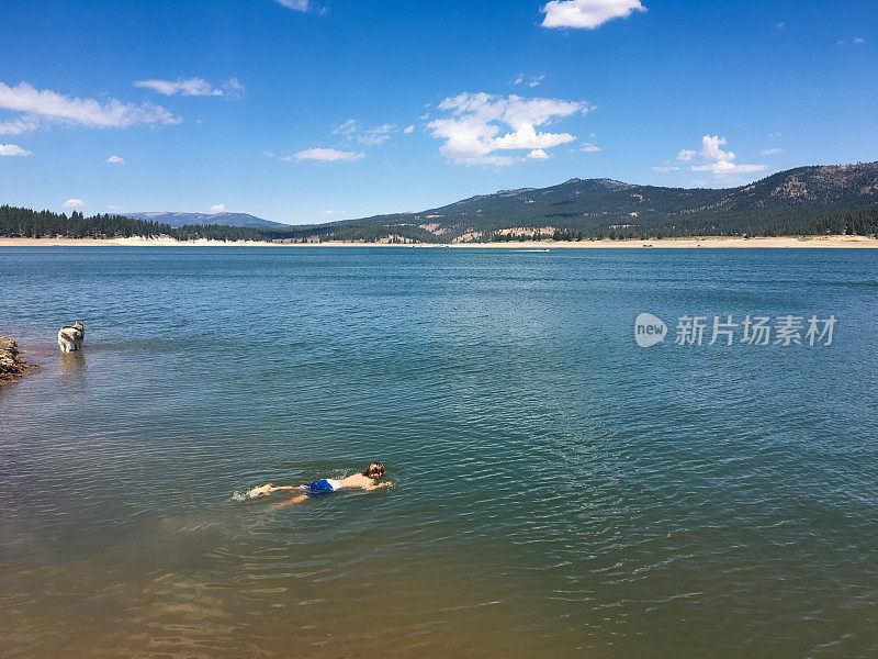 孩子在水下，狗在一旁看着