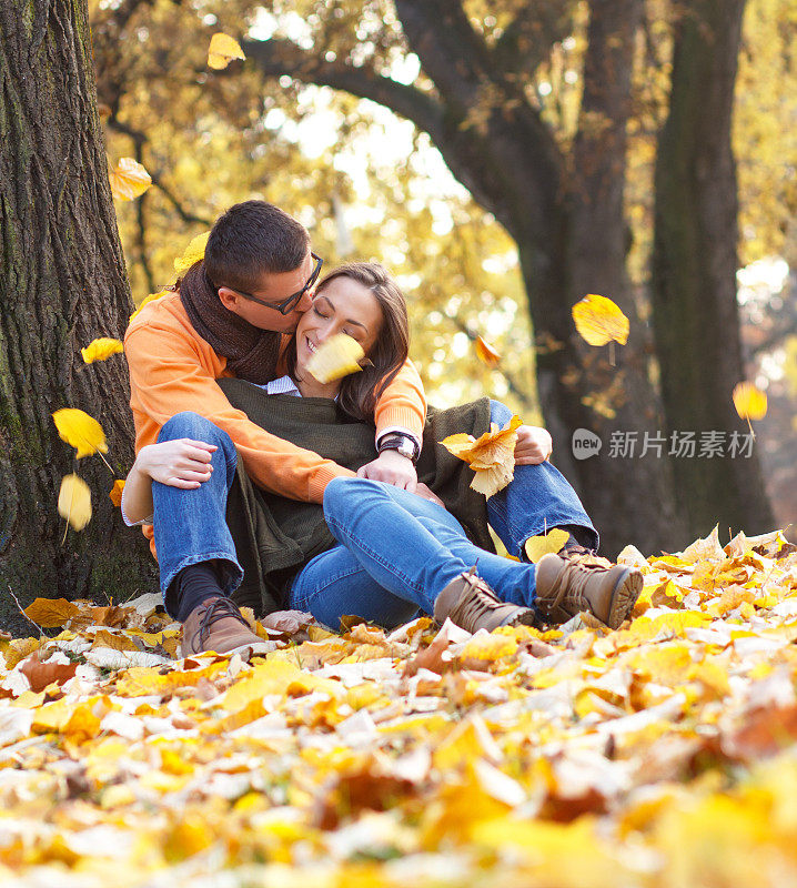 一对年轻夫妇坐在公园的树下