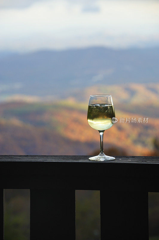 酒杯白葡萄酒在栏杆上，落下背景