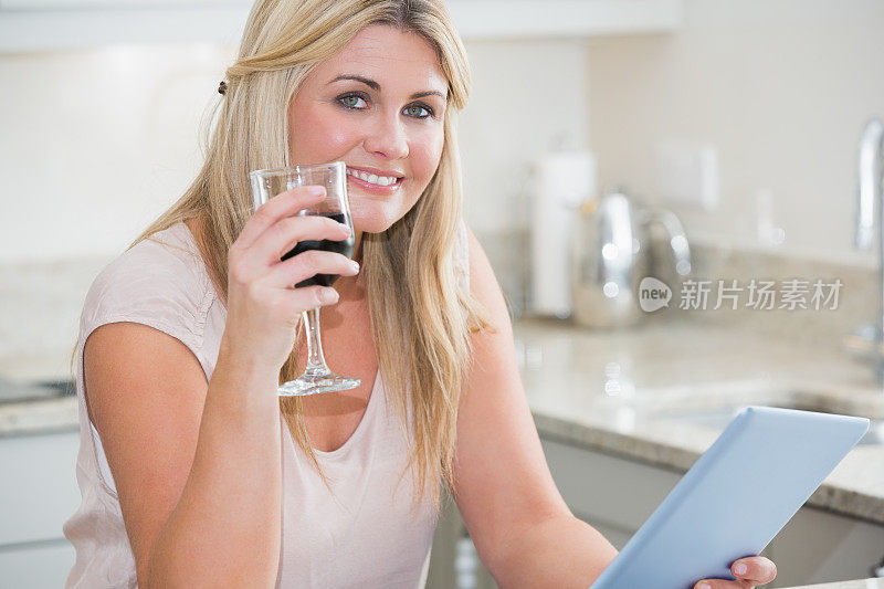 用数码平板电脑拿着酒杯的女人的肖像