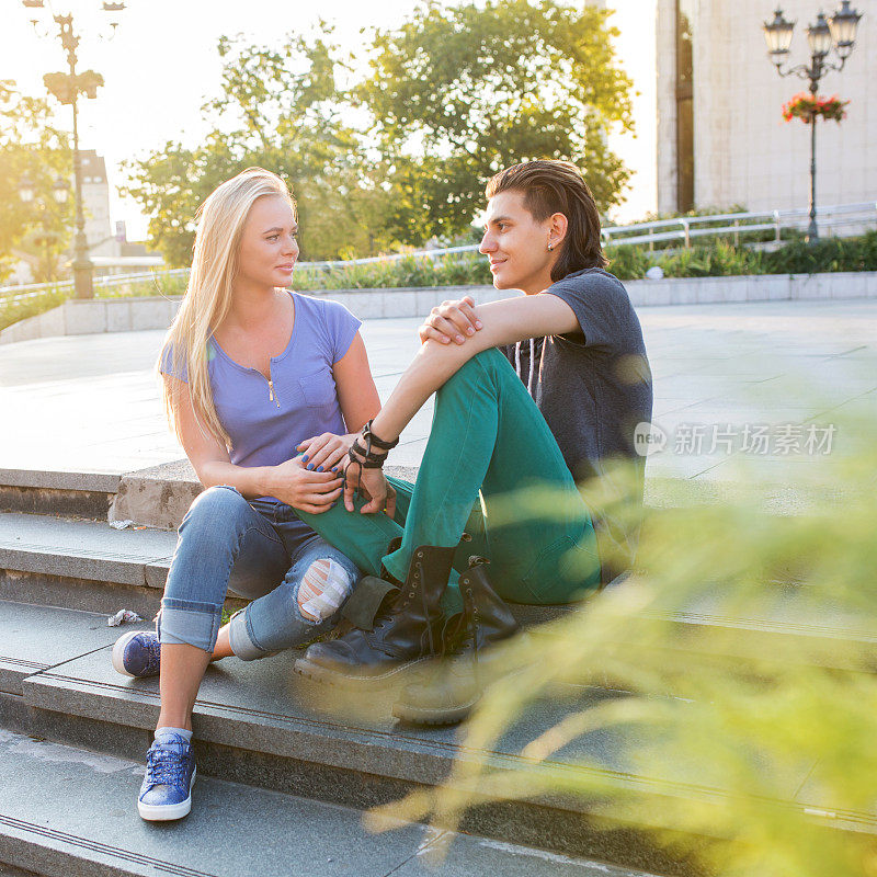 一对微笑的情侣坐在台阶上聊天。