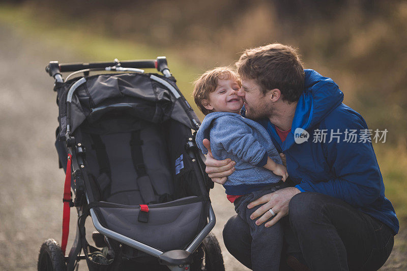 年轻的爸爸和婴儿车里的男孩