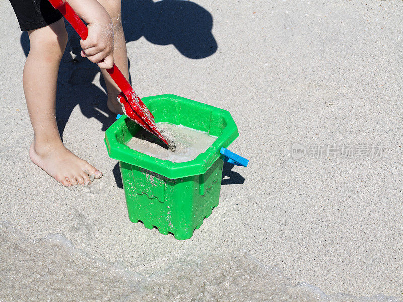 孩子们在海滩上玩水桶和铲子。