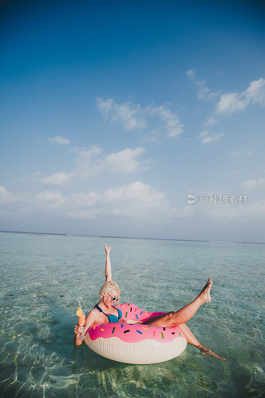 性感的女人浮在水上，有鸡尾酒时间在海洋，马尔代夫