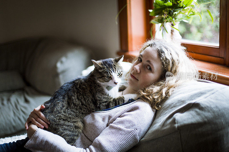 一个女孩和一只猫一起坐在沙发上