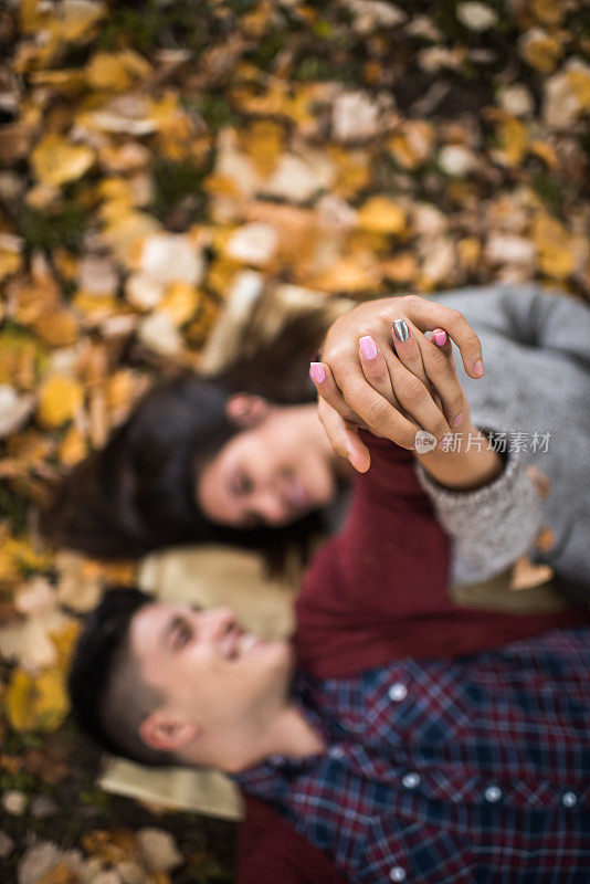 一对夫妇在秋天牵着手的特写。