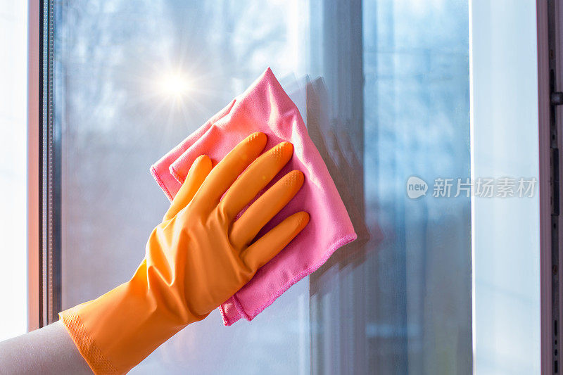 手拿橡胶手套擦窗户。
