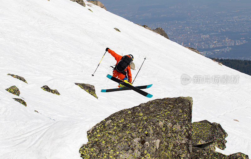 自由式滑雪者用一个技巧飞越一块岩石