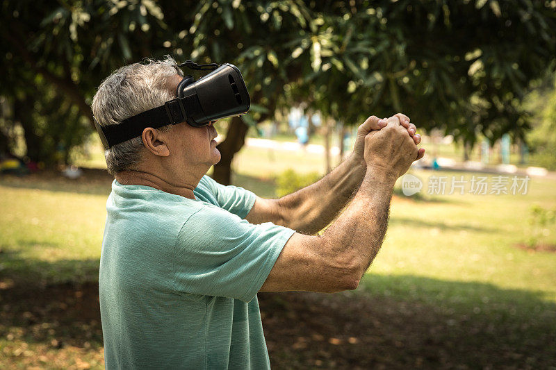 在公园里戴着虚拟现实眼镜的活跃的老年人