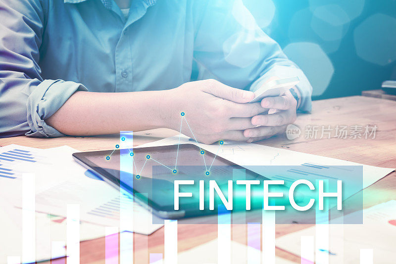 金融科技(FinTech)概念与年轻的创业男子使用智能手机搜索股票数据信息。