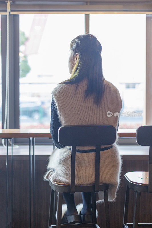 女人坐在咖啡馆的后视图