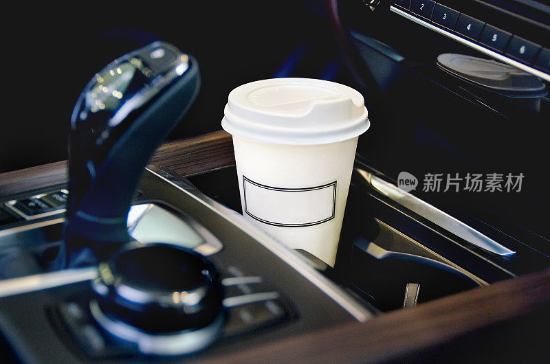 在汽车沙龙喝咖啡。汽车杯架里的一个纸咖啡杯。