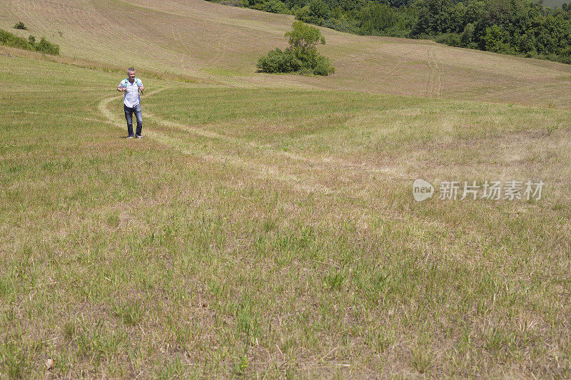 一个成年人在阳光明媚的夏日徒步穿越乡村的草地