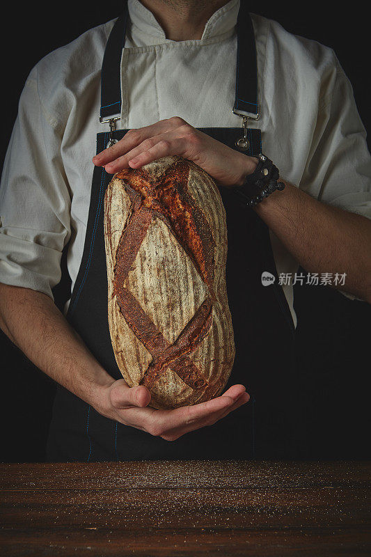 男人手里拿着一个椭圆形的新鲜面包