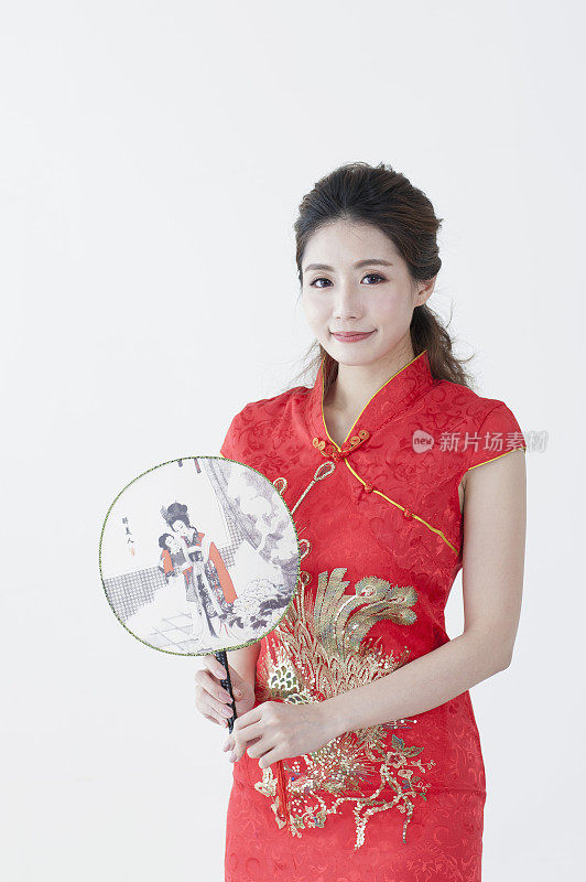 年轻女人穿着旗袍拿着画有国画的扇子