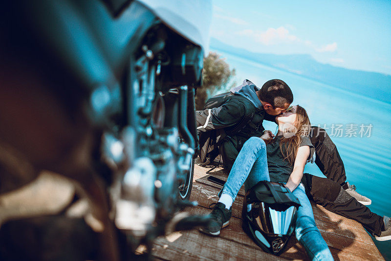 一对可爱的情侣在湖边的木制甲板上接吻