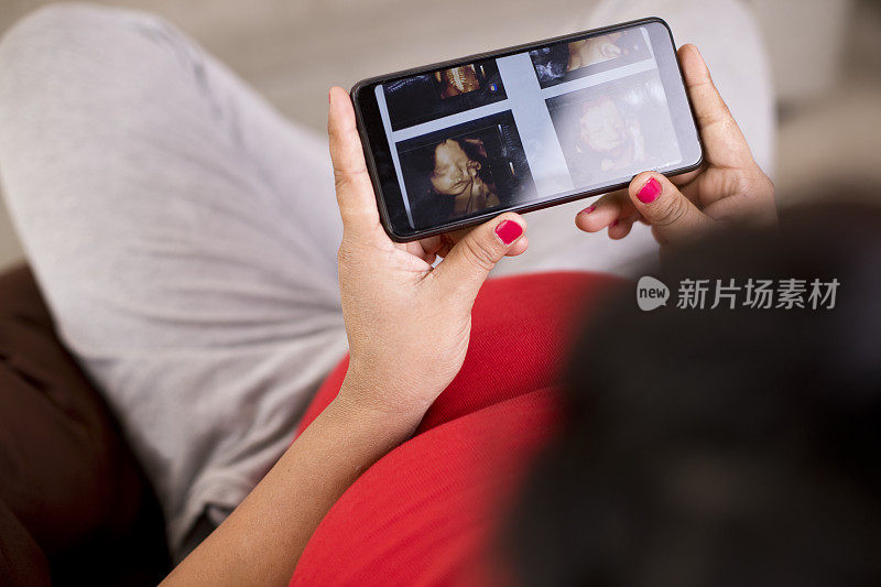 孕妇在手机上看她孩子的超声波照片