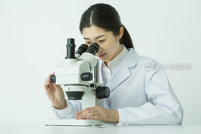 在显微镜下观察的中年女性研究员