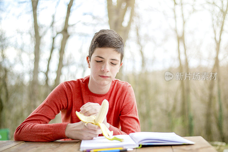 一个在城市公园里学习的少年。吃健康零食的时间到了