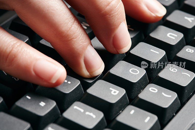 女性手指在黑色的电脑键盘上打字
